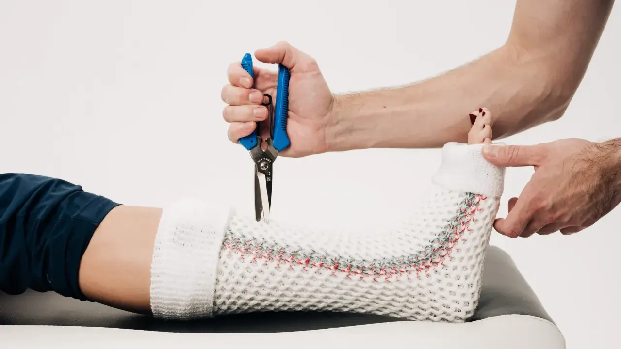 Lekarz zdejmuje gips z nogi pacjenta, przygotowując do zmiany na ortezę. Po jakim czasie można zmienić gips na ortezę?
