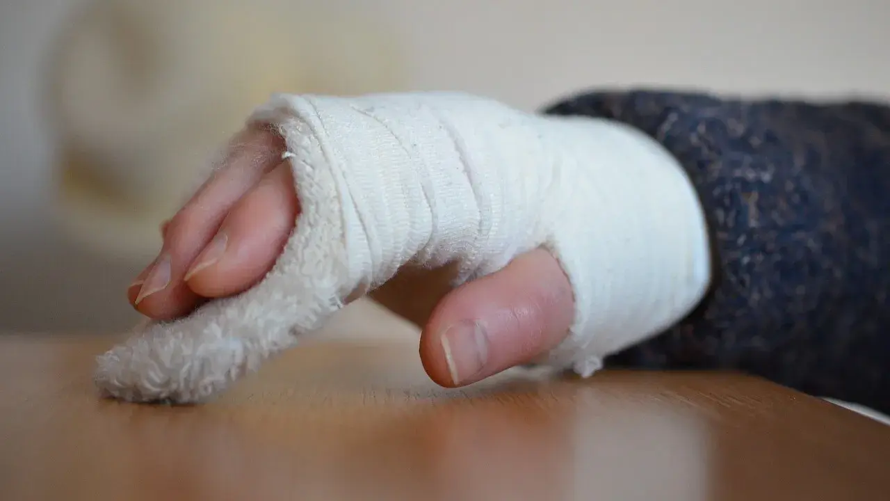 Dłoń w bandażu, z widocznymi palcami. Zastanawiasz się, jak długo trwa rehabilitacja po złamaniu nadgarstka?