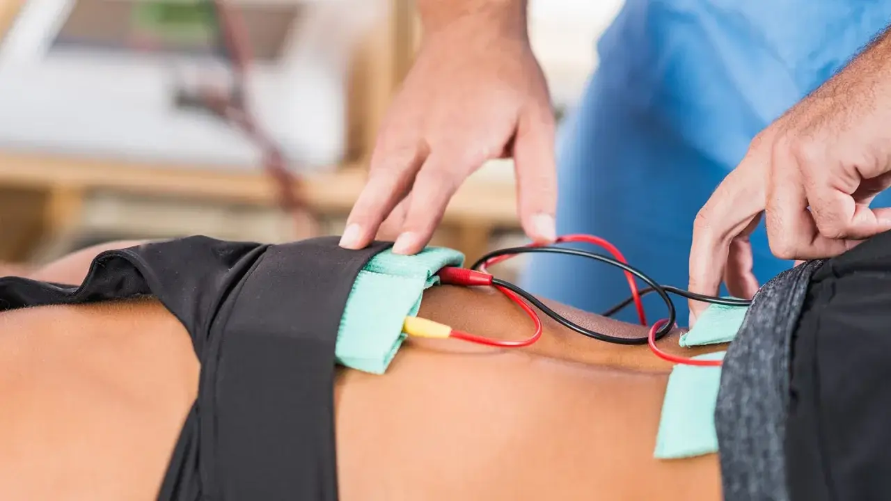 Fizjoterapeuta podłącza elektrody do pacjenta, rozpoczynając zabieg galwanizacji.