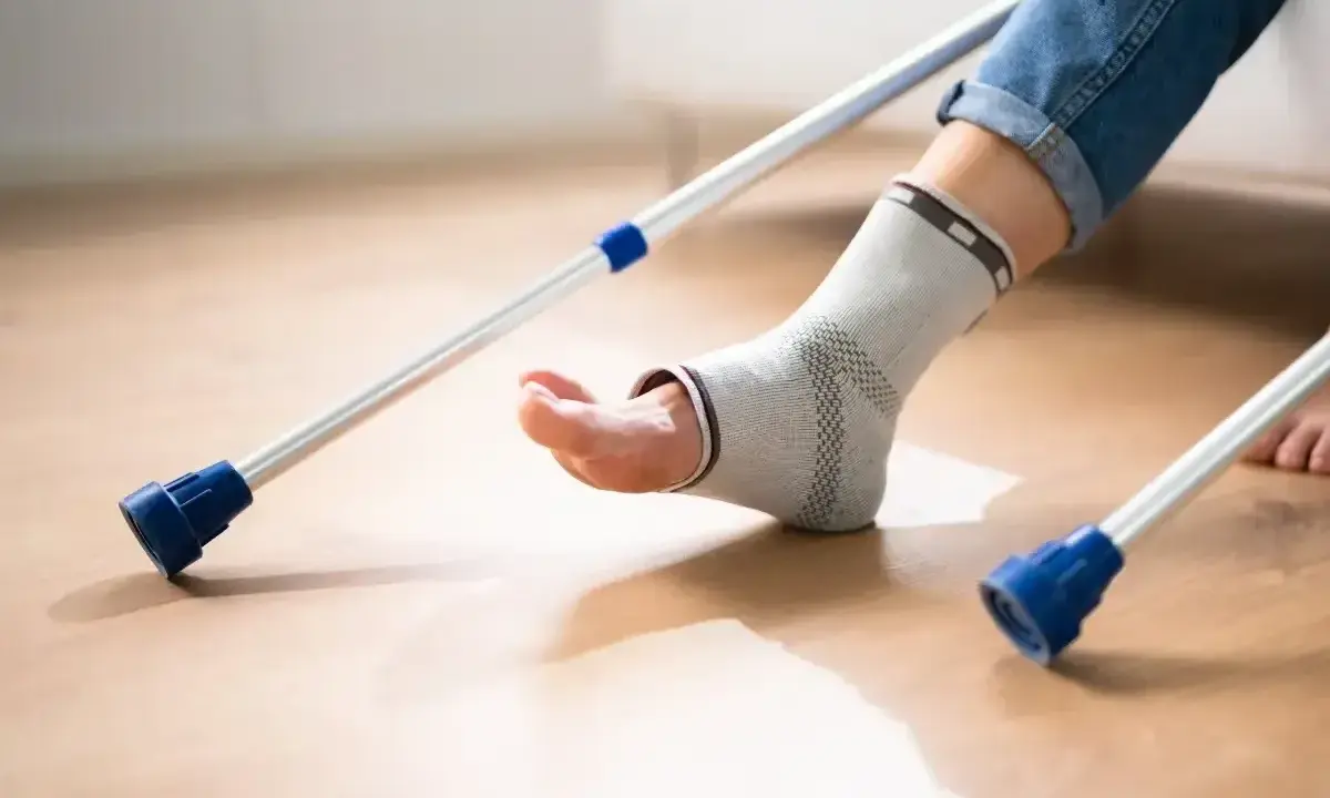 Noga w ortezie kostki, podparta kulami łokciowymi, czeka na powrót do zdrowia.