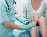 Lekarz bada zbity mięsień czworogłowy uda pacjentki, który jest mocno posiniaczony i zaczerwieniony.