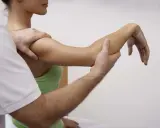 Fizjoterapeuta wykonuje ćwiczenia czynno bierne, delikatnie poruszając ramieniem pacjentki, by przywrócić mu pełną sprawność.