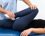 Fizjoterapeuta bada nogę pacjenta, sprawdzając zakres ruchu. Może to pomóc w diagnozie stłuczenia biodra objawy.
