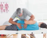 Fizjoterapeuta wykonuje zabieg metodą McKenziego na pacjencie leżącym na kozetce.