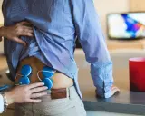 Elektrostymulacja jak często? Terapeuta umieszcza elektrody na plecach pacjenta, przygotowując go do zabiegu.