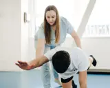 Fizjoterapeutka pomaga pacjentowi w ćwiczeniach, pokazując, co to jest mobilizacja w rehabilitacji.