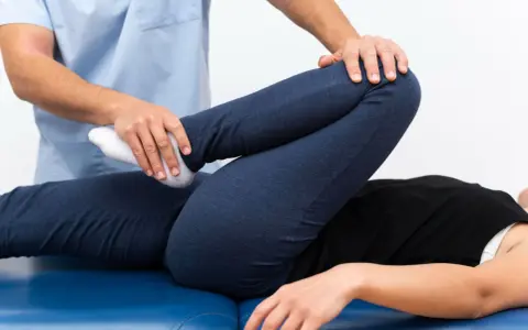 Fizjoterapeuta bada nogę pacjenta, sprawdzając zakres ruchu. Może to pomóc w diagnozie stłuczenia biodra objawy.