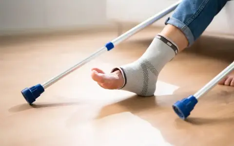 Noga w ortezie kostki, podparta kulami łokciowymi, czeka na powrót do zdrowia.