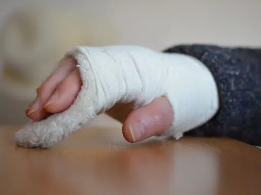 Dłoń w bandażu, z widocznymi palcami. Zastanawiasz się, jak długo trwa rehabilitacja po złamaniu nadgarstka?