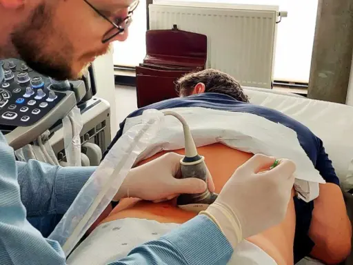 Lekarz wykonuje badanie USG kręgosłupa, skupiając się na ocenie stawów międzykręgowych pacjenta.