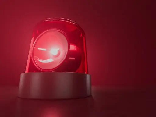 Czerwona lampa ostrzegawcza miga, jakby wzywała do pilnego działania. Jej światło rozchodzi się w czerwonej mgle, przypominając o czymś ważnym, niczym bociani chód zapowiadający zmiany.