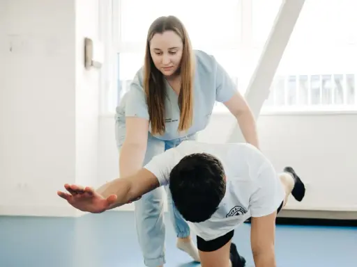 Fizjoterapeutka pomaga pacjentowi w ćwiczeniach, pokazując, co to jest mobilizacja w rehabilitacji.