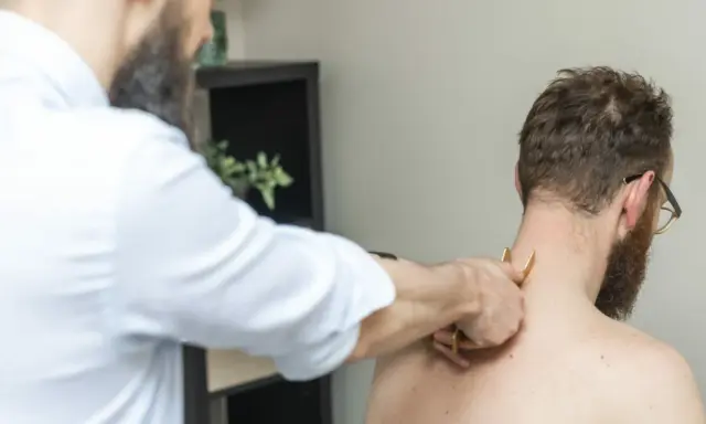 Fizjoterapeuta wykonuje masaż karku pacjentowi. Czasem po rehabilitacji odczuwamy większy ból, ale to część procesu powrotu do zdrowia.