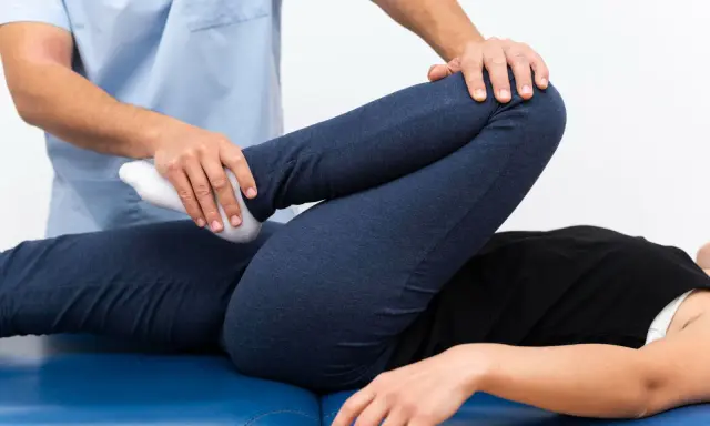 Fizjoterapeuta bada nogę pacjenta, sprawdzając zakres ruchu. Może to pomóc w diagnozie stłuczenia biodra objawy.