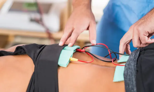 Fizjoterapeuta podłącza elektrody do pacjenta, rozpoczynając zabieg galwanizacji.