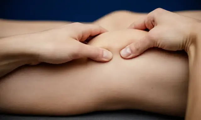 Fizjoterapeuta wykonuje masaż stawu kolanowego, pomagając w leczeniu chondromalacji rzepki. Ćwiczenia wzmacniające są kluczowe.