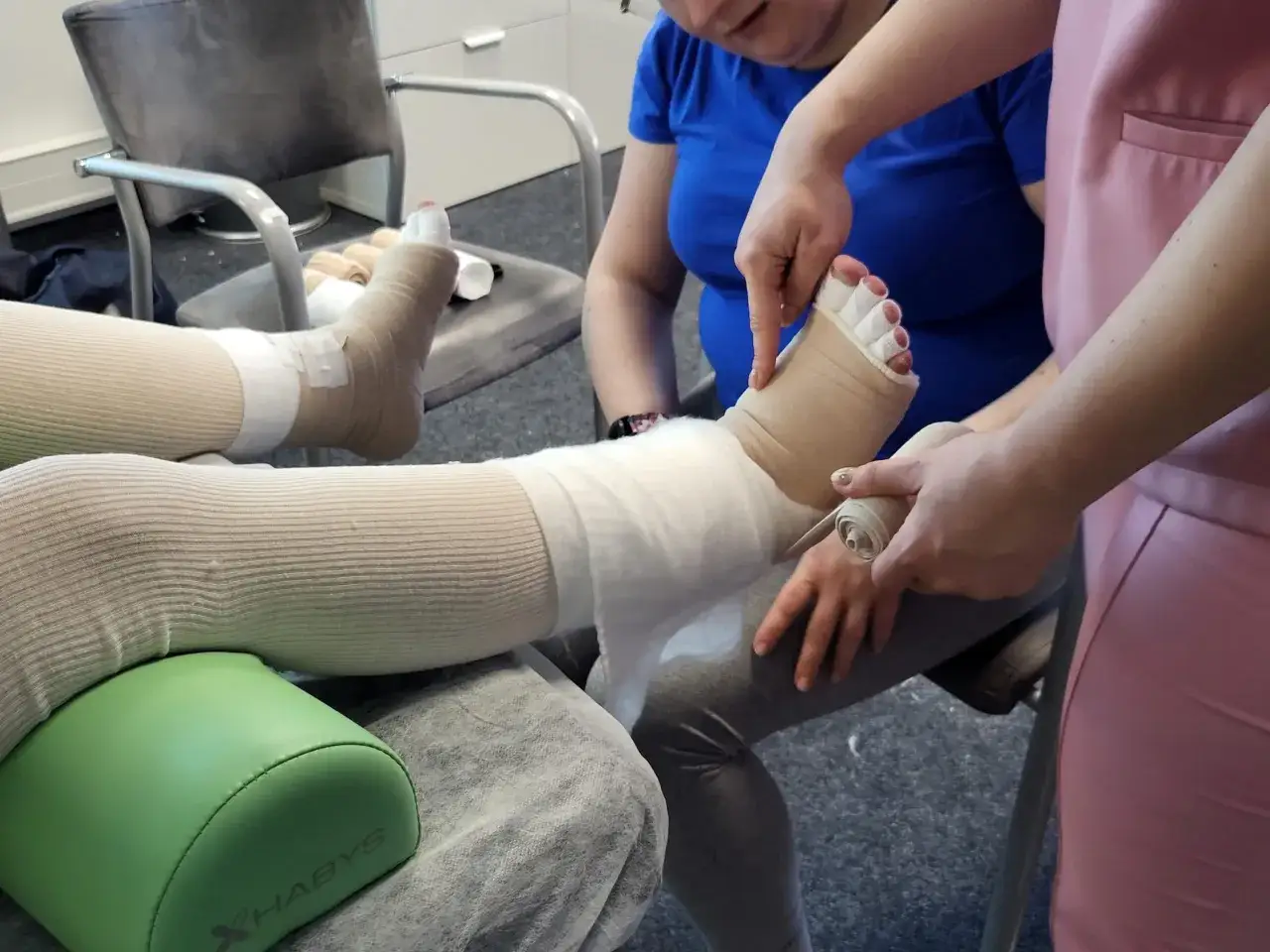 Taping limfatyczny stopy i nogi. Terapeuta zakłada bandaże, by wspom&oacute;c drenaż limfatyczny.