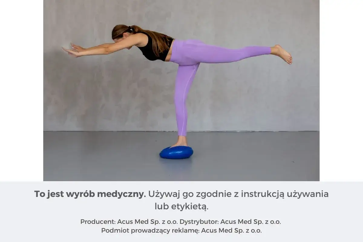 Kobieta wykonuje ćwiczenia na równowagę, stojąc na niebieskiej poduszce sensorycznej. Doskonałe ćwiczenia na czucie głębokie.
